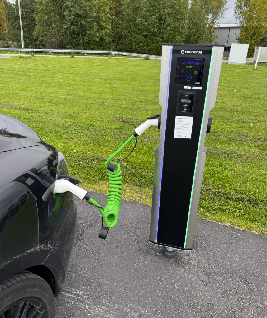 Station de recharge électrique en extérieur, connectée à un véhicule avec un câble de recharge vert en spirale